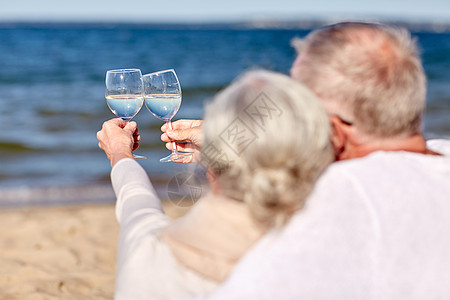 葡萄酒杯家庭龄假期休闲人的夏日海滩上,幸福的老夫妇碰杯背景
