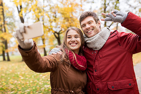 爱情,技术,关系,家庭人的微笑夫妇秋天公园用智能手机自拍图片
