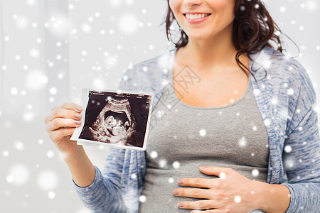 怀孕,冬天人们的近距离的快乐孕妇抱着超声波图像家里的雪图片
