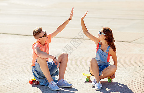暑假,极限运动,手势人的快乐的十几岁的夫妇与短的现代巡洋舰滑板城市街道上高五图片