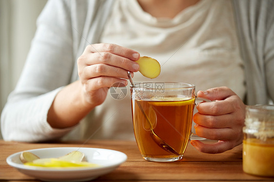 健康,传统医学民族科学的密切妇女添加生姜茶杯与柠檬蜂蜜图片