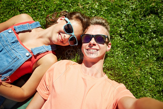 爱人的快乐的青少夫妇戴着太阳镜躺草地上,夏天自拍快乐的十几岁的夫妇夏天的草地上自拍图片