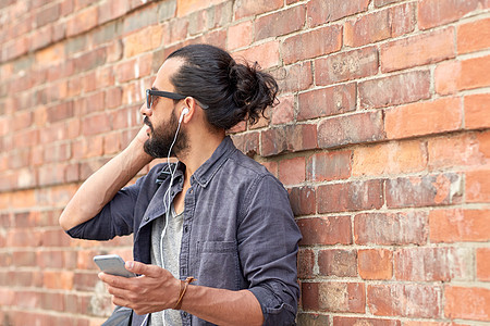 人技术近距离的人与耳机智能手机听音乐砖墙街上带耳机智能手机的男人街上图片