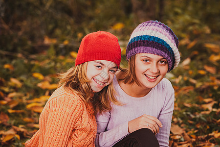 两个友好的姐妹玩着秋叶,微笑着姐妹们玩树叶图片