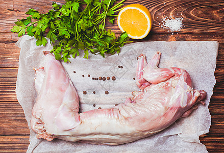 生兔肉与柠檬,盐欧芹木制背景图片