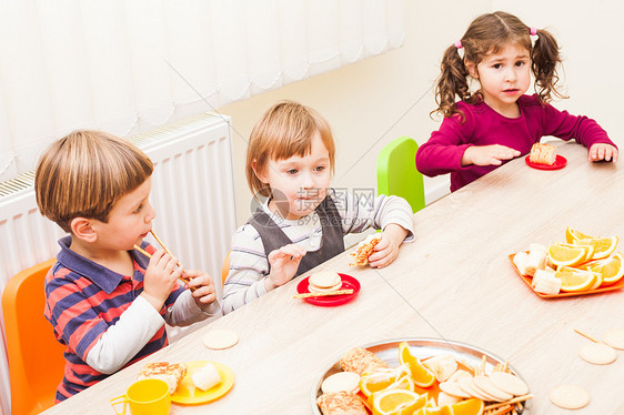 孩子们坐桌子旁吃午饭,吃水果蛋糕幼儿园吃午饭图片