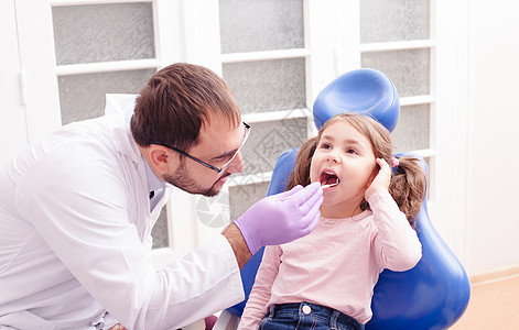 个小女孩的肖像,他张开嘴巴坐着,牙医那里检查牙齿牙医的接待处图片