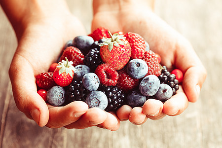 夏季野生浆果手覆盆子,草莓,黑莓蓝莓图片