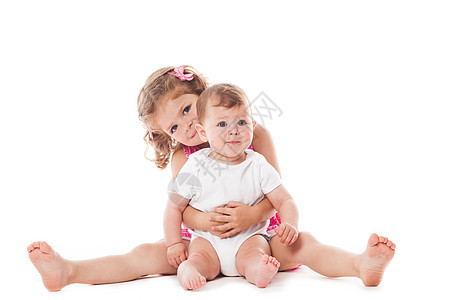 两个可爱的姐妹坐地板上,微笑着隔离白色上两个姐妹被隔离了图片
