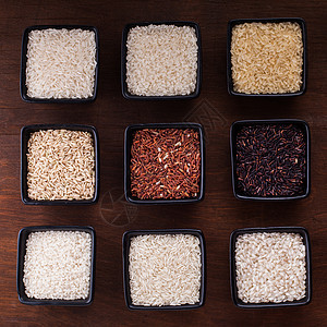 木制桌子上黑色碗里的各种米饭各种类型的大米图片