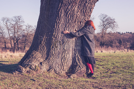 个轻的女人寒冷的冬天拥抱棵大树图片