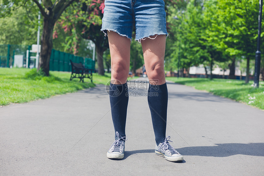 个穿着膝盖高袜子的轻女人夏天站公园里图片