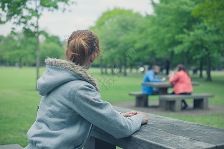 个轻的女人独自坐公园里的张桌子上,正野餐图片