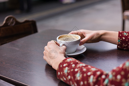 年轻女人的手,街上的张桌子上放着杯咖啡图片