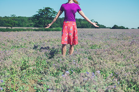 个轻的女人片紫色的花丛中举双臂图片