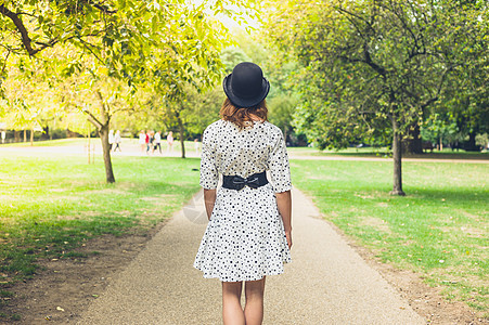 个轻的女人戴着礼帽件白色的连衣裙,个阳光明媚的夏天公园里散步图片