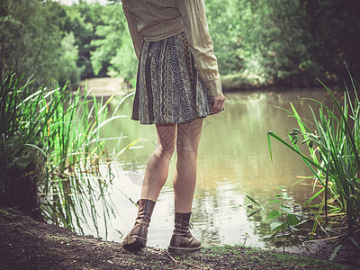 个轻的女人阳光明媚的日子里站森林里的池塘边图片