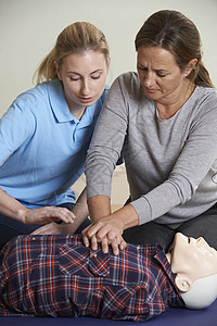 妇女示范CPR训练假人急救课图片