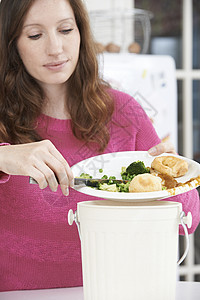 女人把食物剩菜刮进垃圾桶图片