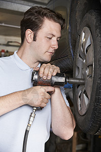 车库机械师汽车车轮上用空气锤图片