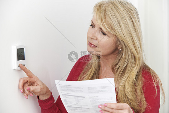 担心的女人用暖气账单恒温器图片