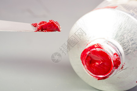 少量的红色油漆用油漆刀的尖端油漆的管子上取下来的图片