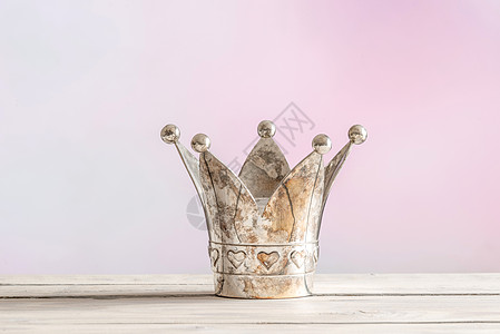 粉红色背景上的木桌上的皇家皇冠图片