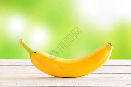 绿色背景上木桌上的单根香蕉图片