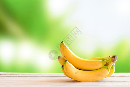 绿色背景上木桌上的黄色香蕉图片