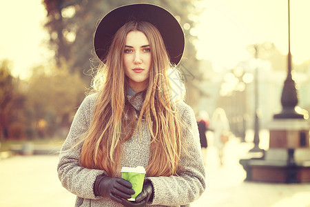 阳光生活方式的照片,轻时尚的时髦女人走街上,戴着可爱的时髦帽子,户外喝热铁咖啡时尚博主服装照片色调风格Insta图片