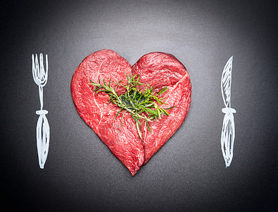 心形的生切肉肉喜欢彩绘餐具叉子刀深色黑板背景吃肉的人食客图片