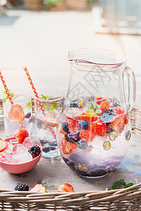 水罐与水,浆果冰块桌子上的花园露台背景家庭场景与夏季饮料图片