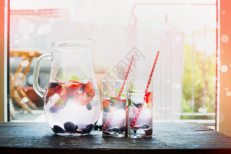 水壶,水,冰块浆果,两个璃杯厨房桌子上的花园露台背景家庭场景与夏季饮料图片