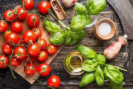 新鲜机樱桃西红柿与罗勒叶橄榄油乡村厨房桌子上,顶部视图图片