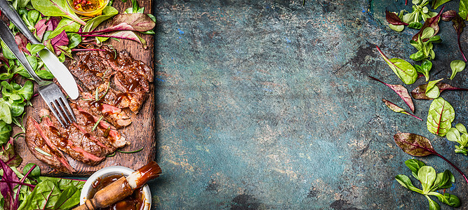 完美的油炸烤牛排切片牛肉seak,与绿色沙拉叶烧烤酱木制切割板乡村背景,顶部视图,横幅图片
