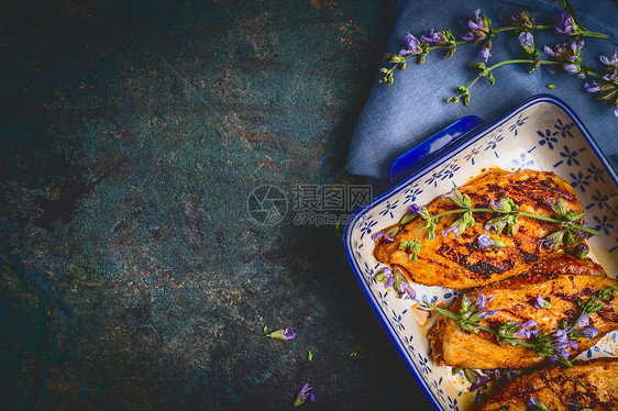 鸡胸烹饪菜与新鲜草药深蓝色乡村背景,顶部视图,地点为文本图片