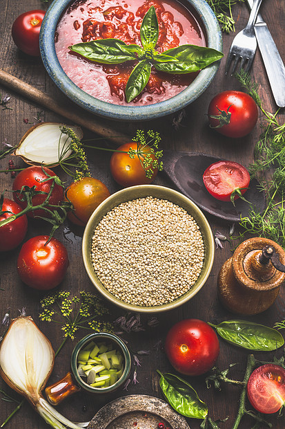 藜麦种子黑暗的厨房桌子上与蔬菜烹饪原料西红柿酱,顶部视图超级食品健康素食食品的图片