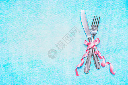餐具粉红色丝带浅蓝色背景,顶部视图,地点为文本桌子位置图片