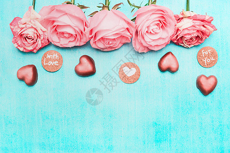 浅粉色玫瑰与巧克力心爱的信息标志绿松石背景,顶部视图节日贺卡图片