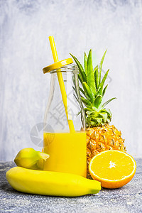黄色冰沙瓶与稻草配料轻木背景,侧视健康的生活方式排饮食的图片