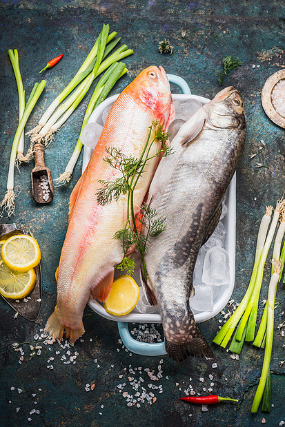 生全鳟鱼金虹鳟鱼菜肴与冰块新鲜的烹饪成分黑暗的乡村背景,顶部视图健康饮食的食物图片