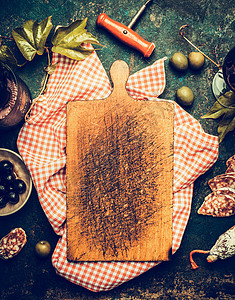传统红色格子餐巾上的空白老化砧板,周围躺着的零食开胃菜葡萄酒橄榄萨拉米葡萄叶意大利食品背景菜单食谱图片