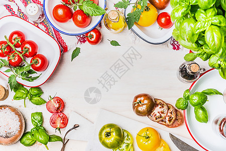 五颜六色的西红柿上的品种与调味品沙拉成分漆包碗美味的夏季烹饪轻木背景,顶部视图,框架图片