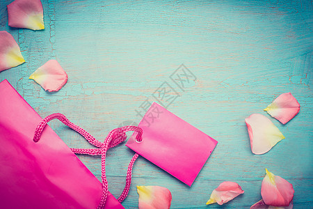 明亮的粉红色纸购物袋与花瓣上的蓝色绿松石破旧别致的背景,顶部的视图,地方为文字,边界夏季特价出售复古风格图片