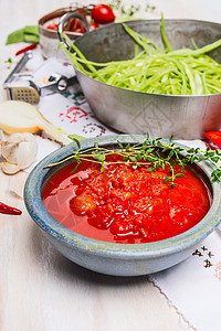 厨房桌子上放着西红柿酱的碗,配上炊具绿色蔬菜,关门图片