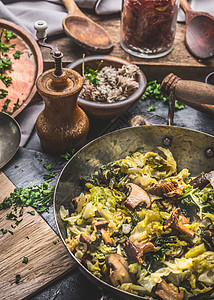 素食砂锅与炖卷心菜蘑菇黑暗的乡村厨房桌子上与烹饪原料图片