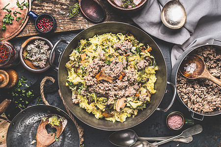 砂锅与米饭,切碎的卷心菜碎肉乡村厨房的桌子上,用木制勺子碗与调味品香料,顶部的景色背景图片