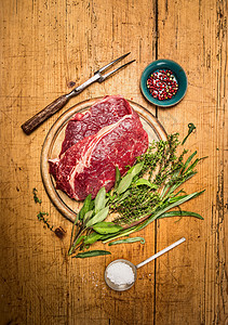 生牛排配肉叉,新鲜草药勺板条乡村木制背景,顶部视图图片