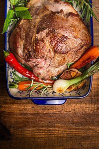 烤羊腿与蔬菜草药砂锅碗乡村木制背景,顶部的视图,图片