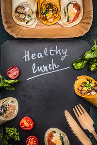 健康的午餐刻字与素食包装木制餐具深色黑板,顶部视图,框架图片